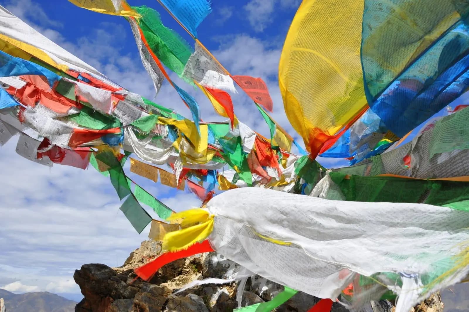 une multitude de petits drapeaux multicolores s'agitent au vent sur les montagnes du Tibet