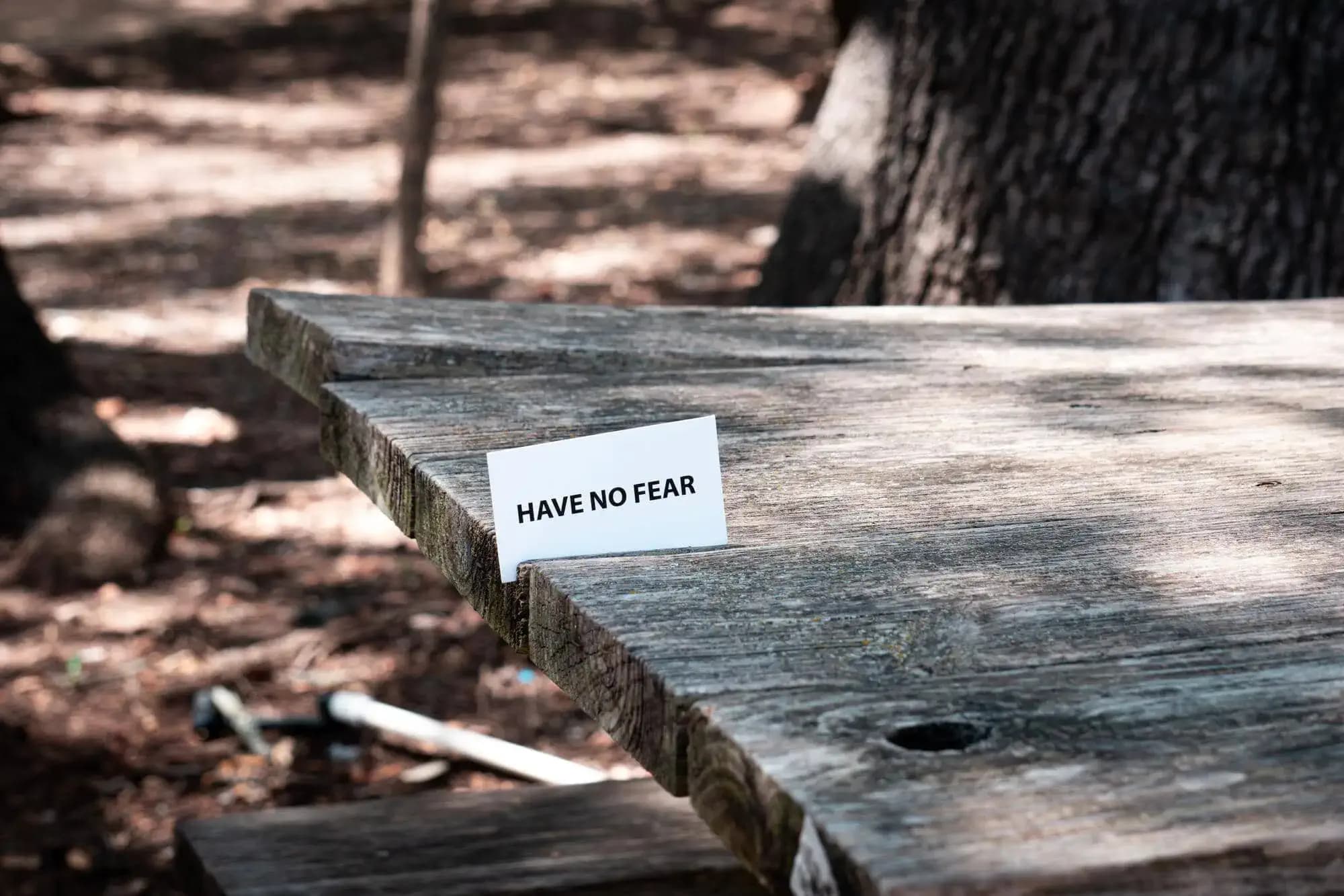 Une table en bois avec un petit papier avec la mention "have no fear"